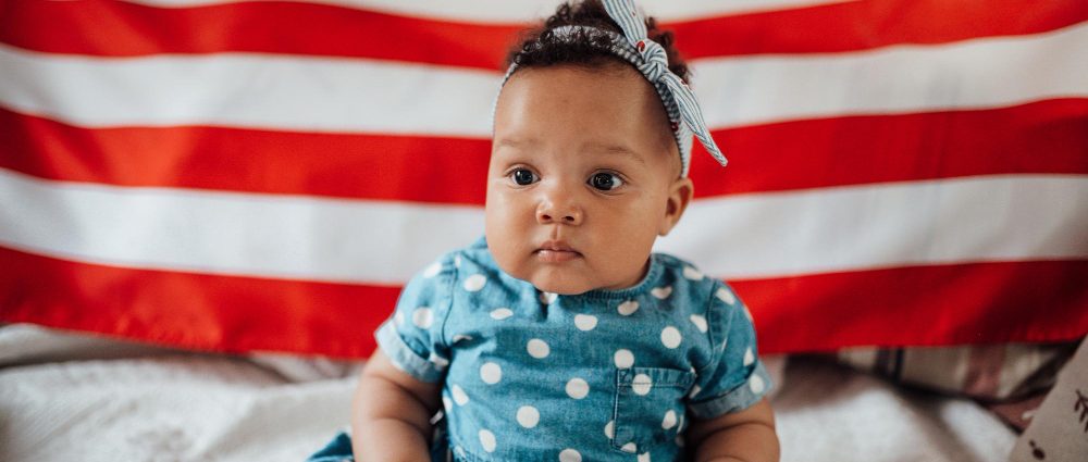 A baby girl in front of an US flag