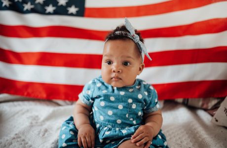 A baby girl in front of an US flag