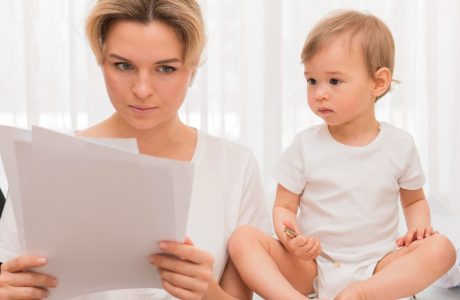 A mother reading paper and a baby watching